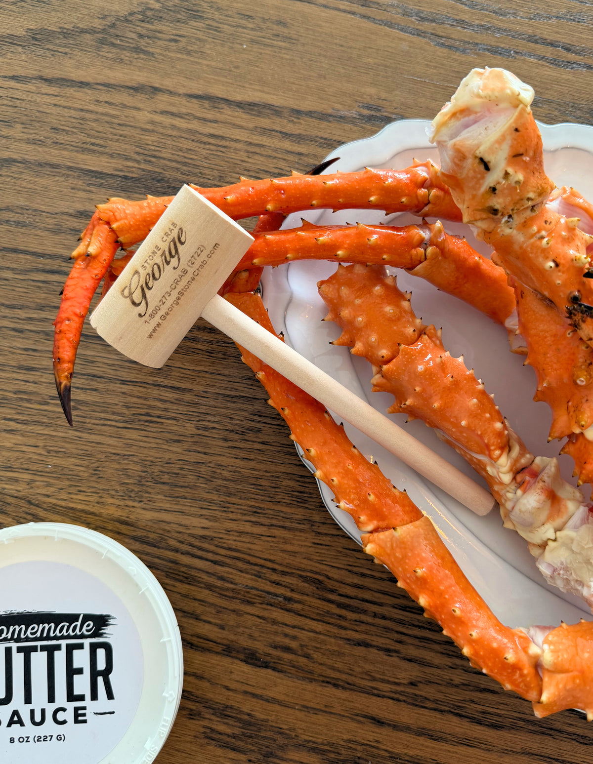 Alaskan King Crab Legs Crab legs with a wooden mallet and container of butter sauce on a wooden surface