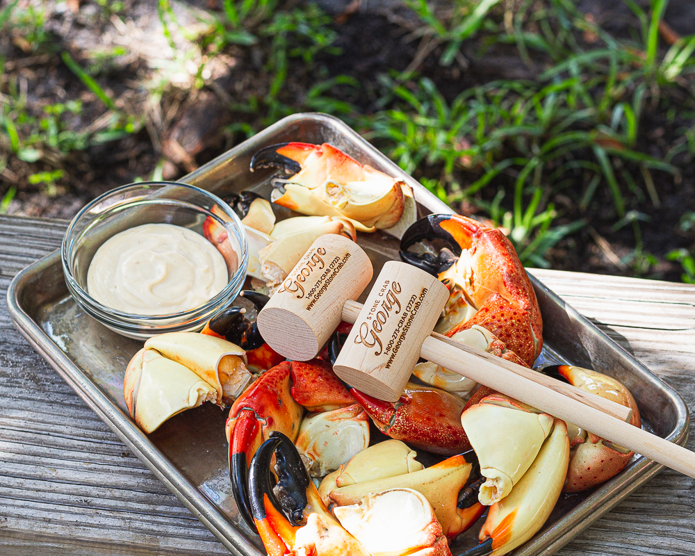 Stone crab claws on a metal tray accompanied by our famous sauce and two mallets